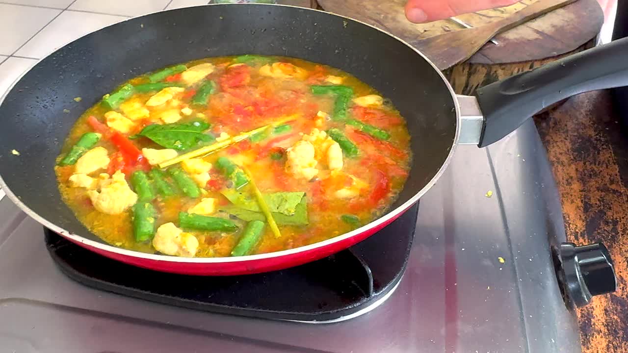 将椰奶加入到美味的印尼鸡肉和蔬菜椰子咖喱中，在煤气灶上煨煮视频下载