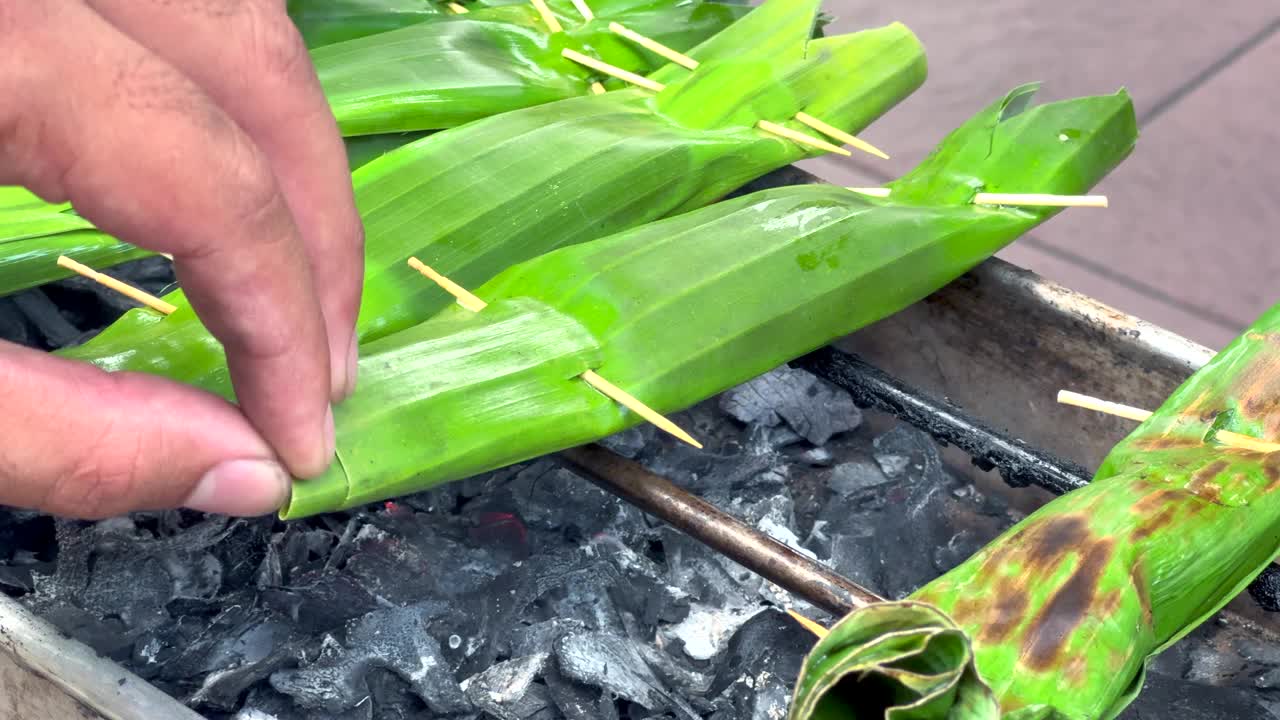 传统的巴厘岛烹饪，厨师将裹在香蕉叶里的金枪鱼放在小烤架上，在热煤上蒸视频下载