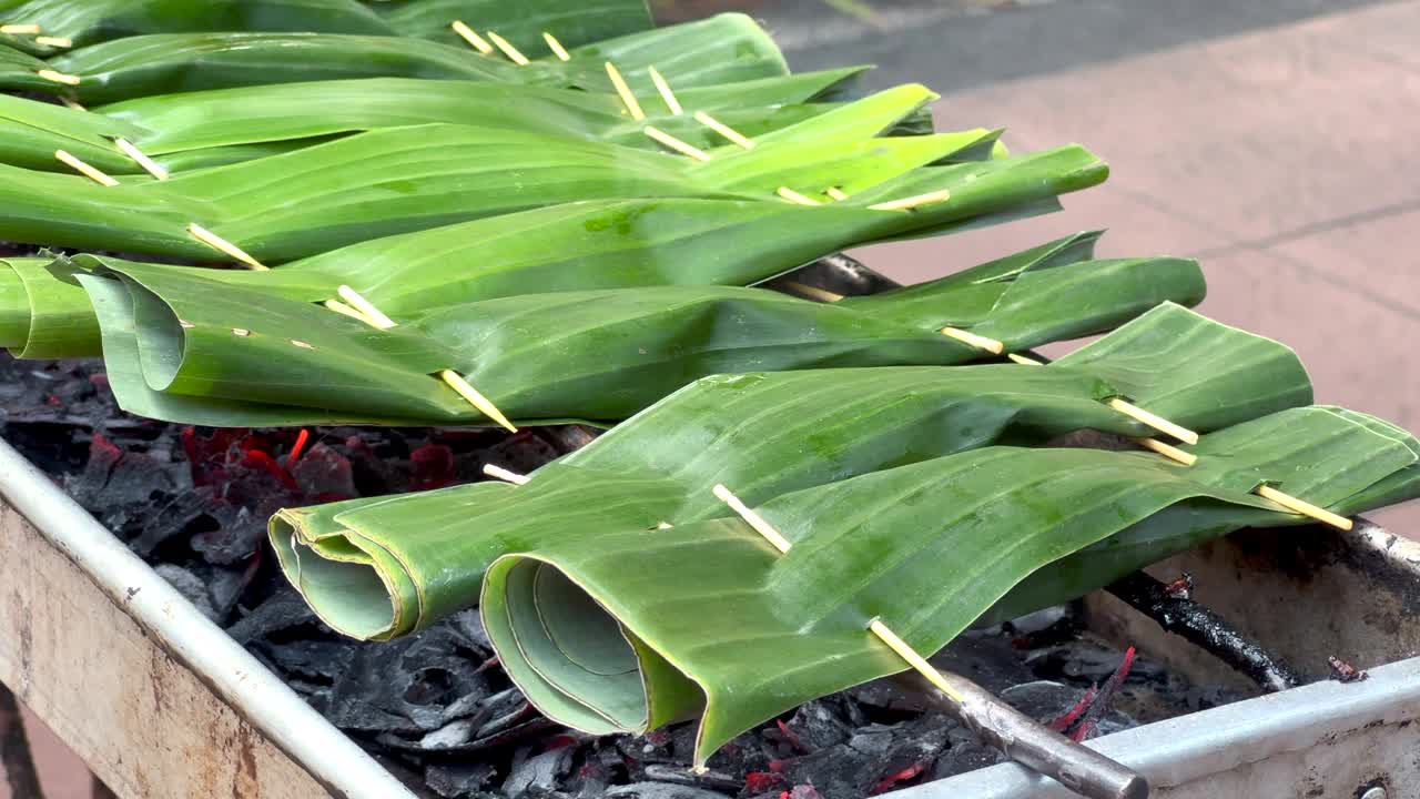 传统的巴厘岛料理，新鲜的绿色香蕉叶填满金枪鱼在热煤上蒸视频下载