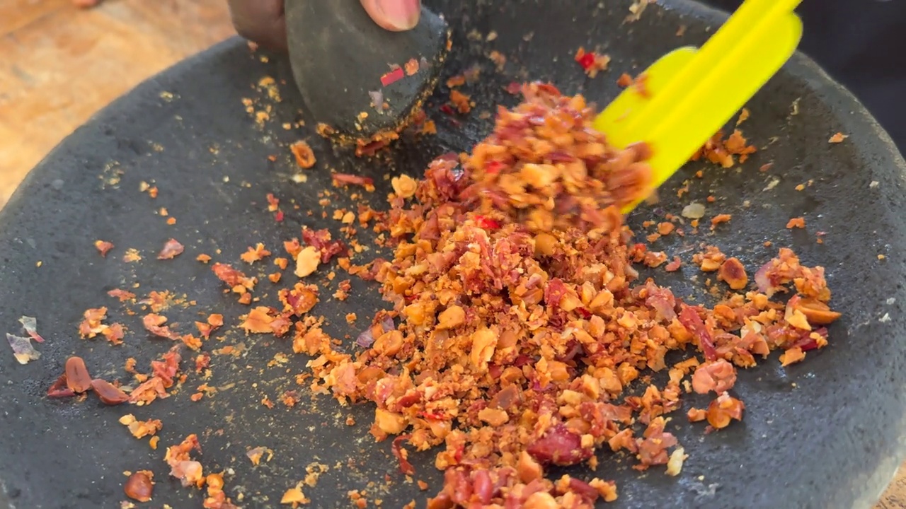一位家庭厨师用研钵和杵把花生和辣椒磨成沙茶酱，用于传统的印尼烹饪视频下载