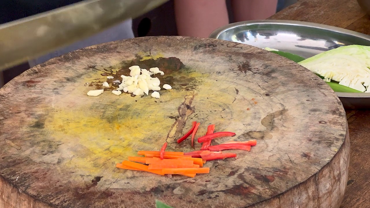 亚洲厨师熟练地用一把大刀在砧板上切大蒜，然后切白菜叶视频下载