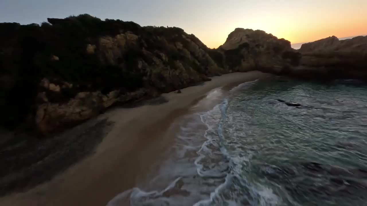 日出时两个人站在海岬上的鸟瞰图。视频下载