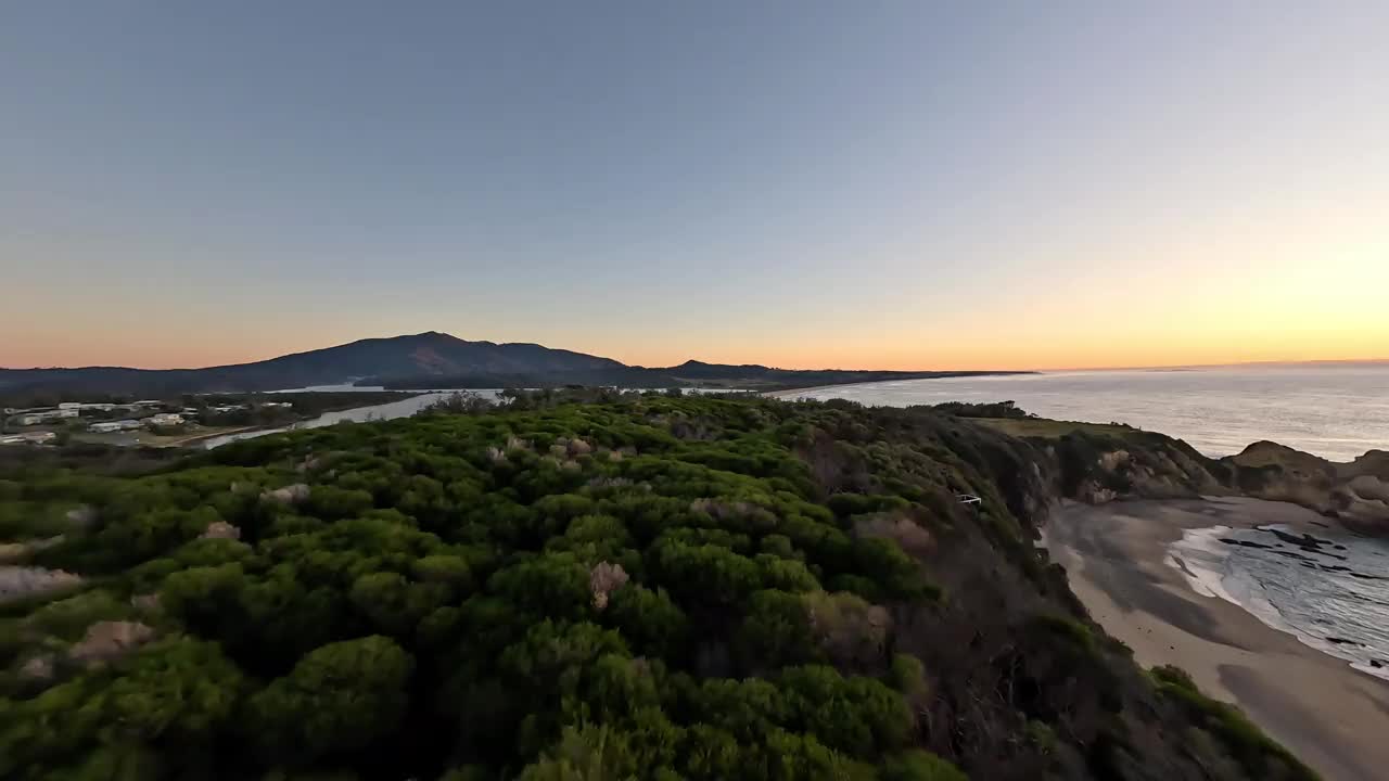 海岬的鸟瞰图，两个人在悬崖顶上观看日出。视频下载