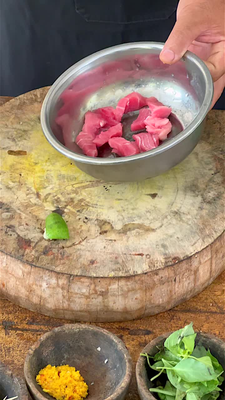 一名厨师在一碗生金枪鱼中加入盐和胡椒，淋上椰子油给鱼调味，这是美味的巴厘岛传统美食的一部分视频素材