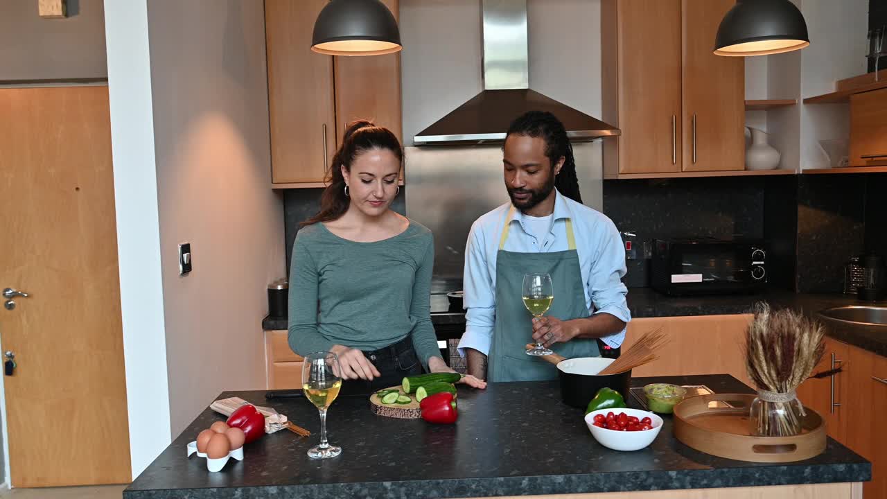 一对英国夫妇在现代厨房里准备食物。女人在切黄瓜，男人在煮意大利面视频下载