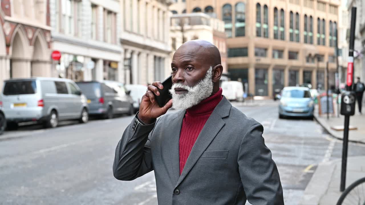 加勒比裔的成熟商人，在金融区用智能手机说话，表情严肃视频下载