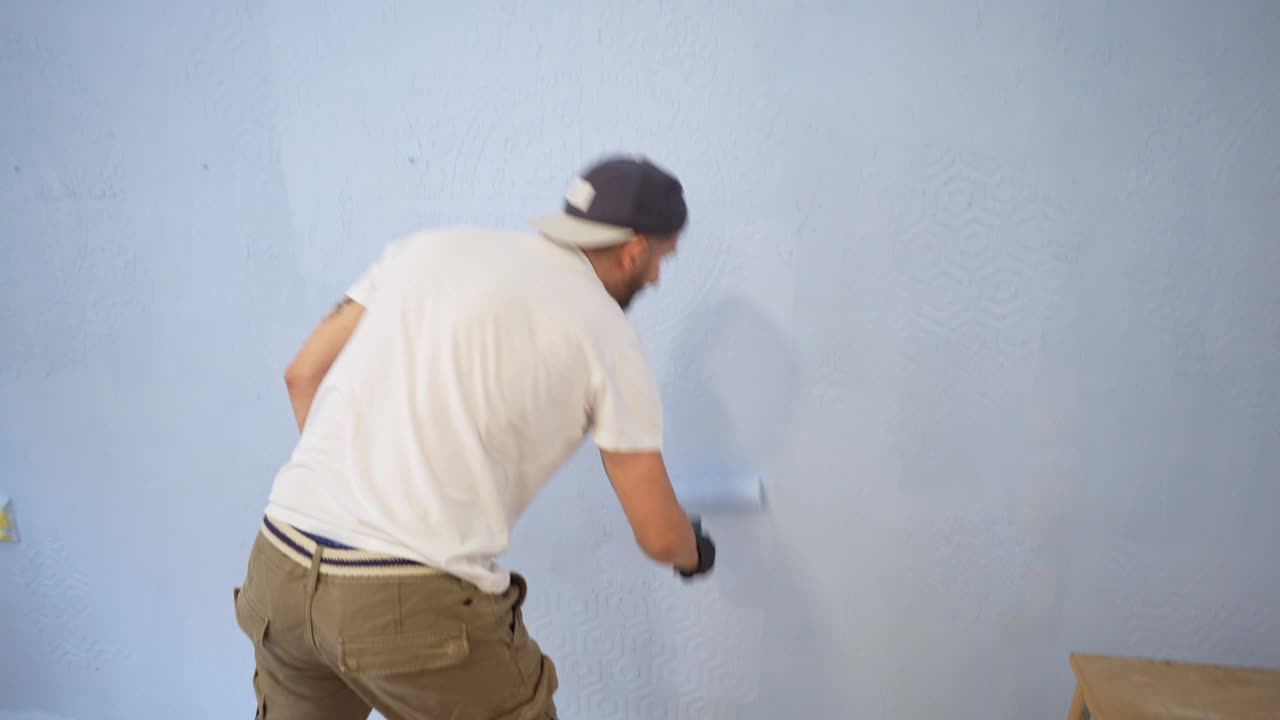 后视镜:一个白人杂工正在用浅蓝色的油漆粉刷自己公寓的墙壁视频下载