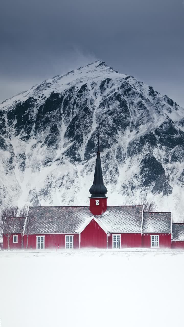 斯堪的纳维亚冬季的自然景观，白雪皑皑的海岸山峰和古老的挪威红教堂，垂直视频视频下载
