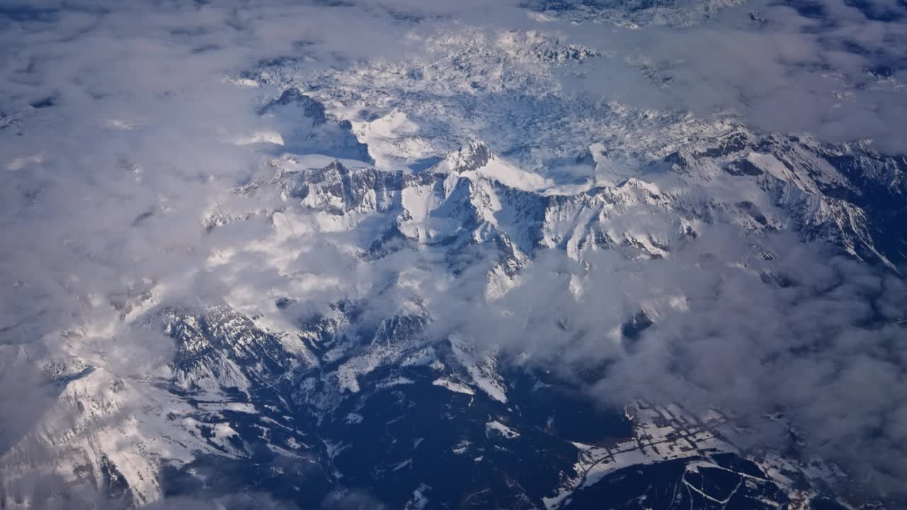 飞行与飞机在蓬松的白色积云和雪山高峰高空大气视频视频下载