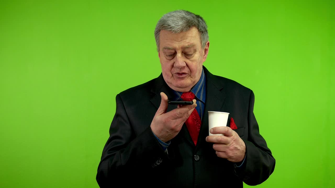 西装革面的老人一边喝着咖啡，一边用智能手机录着语音信息。视频下载