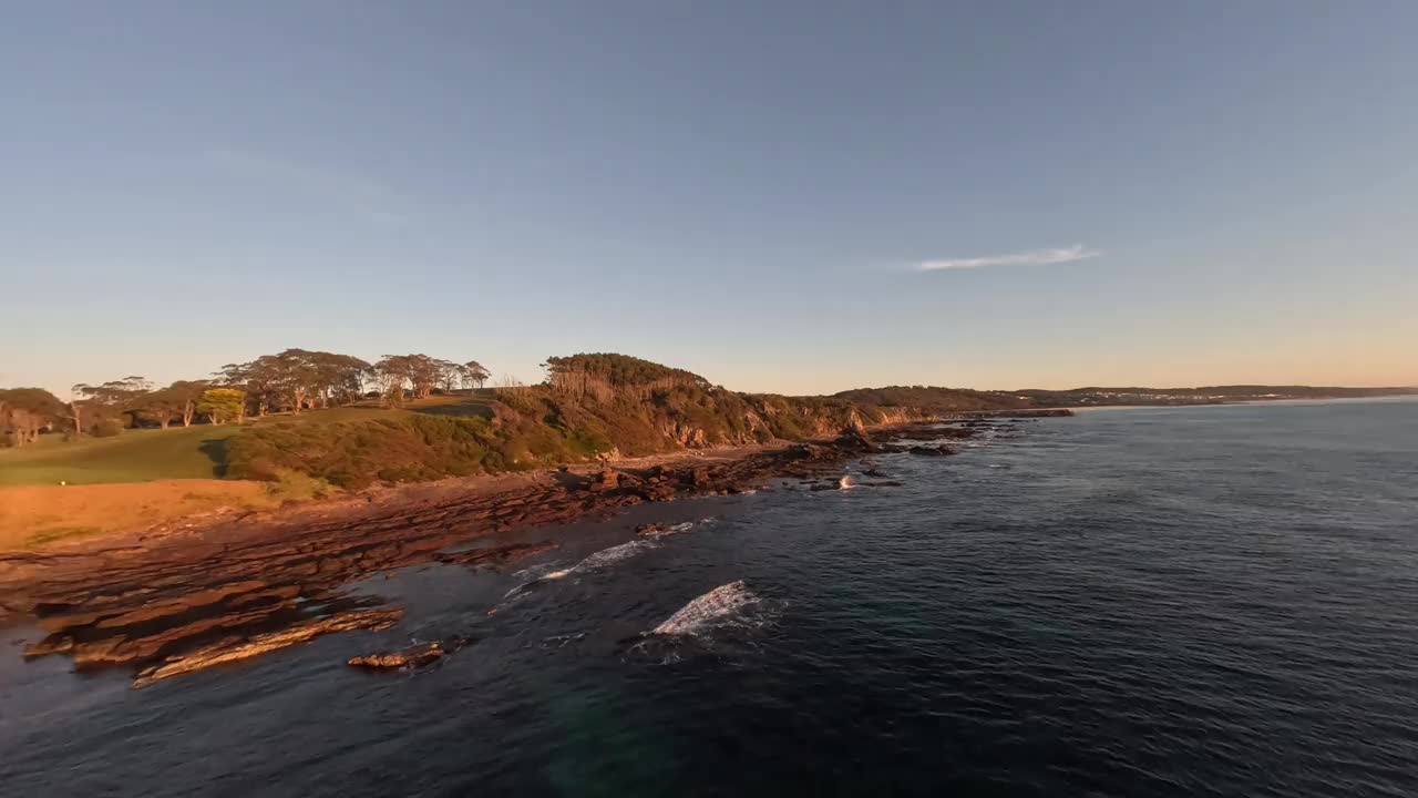 日出时沿着岩石海岸线的鸟瞰图。视频下载