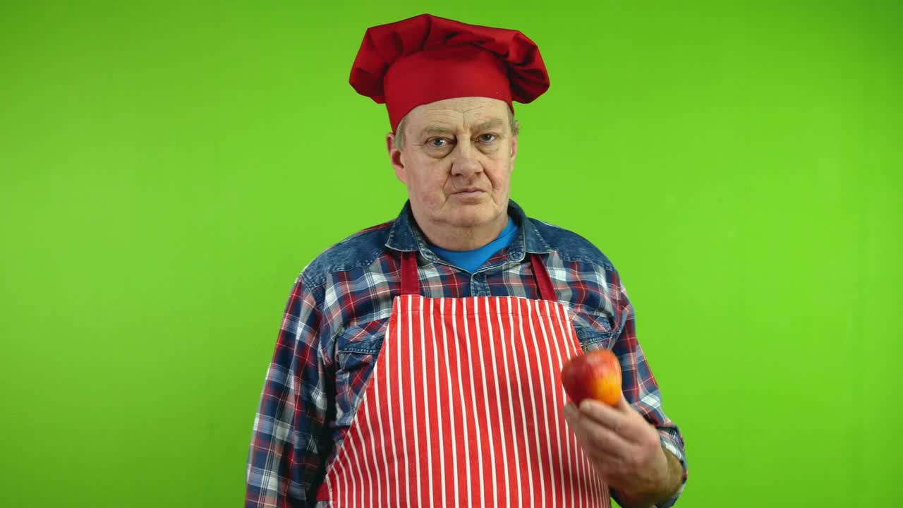 积极的高级厨师展示成熟的苹果，谈论好处并给水果。视频下载