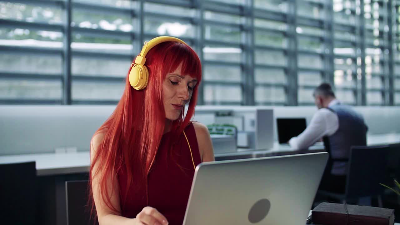 成熟的女商人坐在办公室的办公桌前，使用笔记本电脑。视频下载