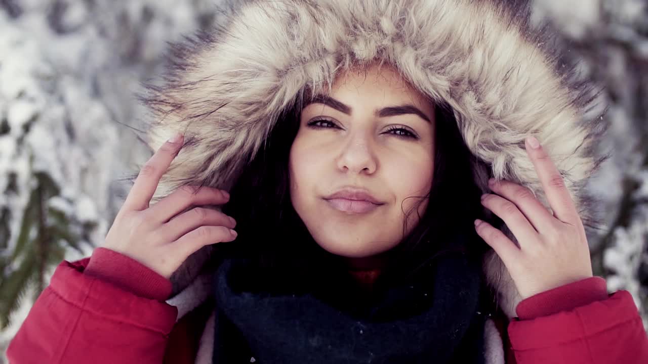 一名年轻女子站在白雪皑皑的冬季森林中。视频下载