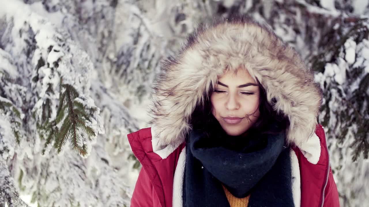 一名年轻女子站在白雪皑皑的冬季森林中。视频下载