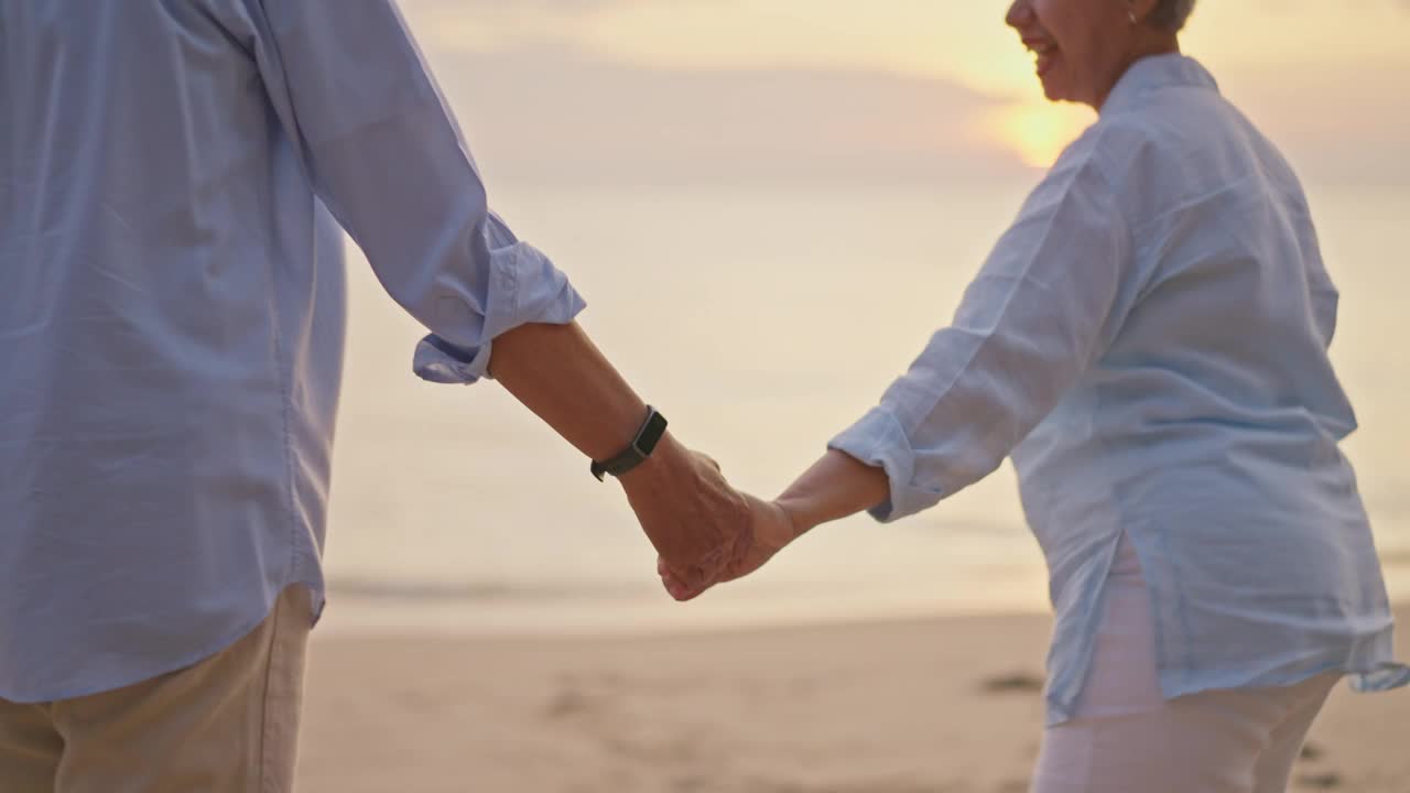 夕阳下，一对快乐的老年夫妇在海滩上跳舞。视频下载