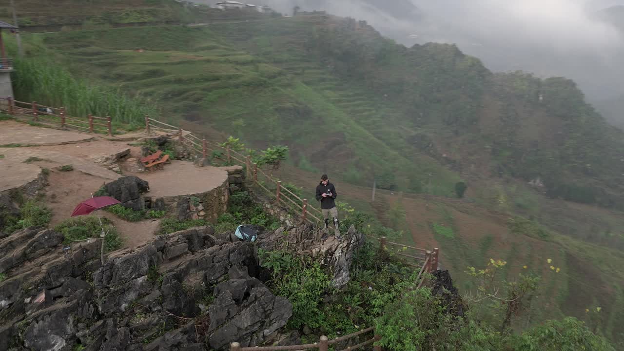 视差环绕拍摄的一个男人站在悬崖边的岩石在越南山区。视频下载