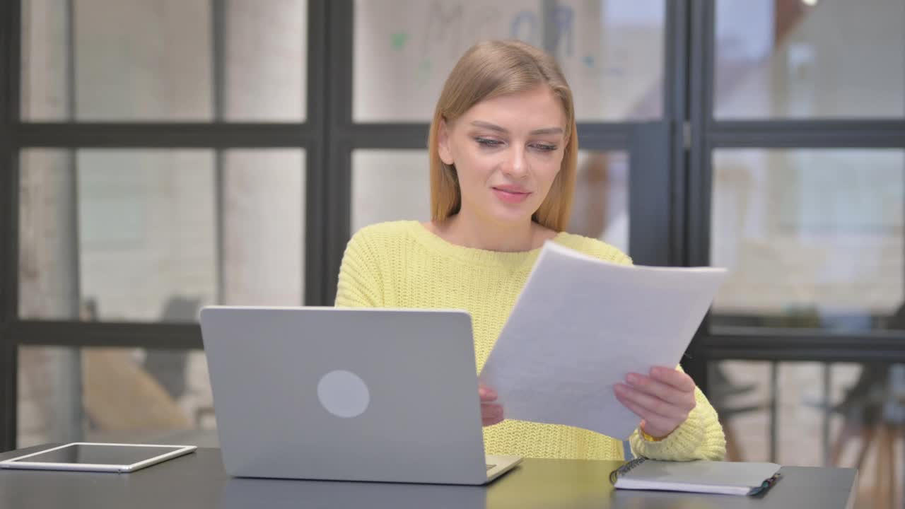 休闲创意女性在处理文件和笔记本电脑时庆祝视频下载