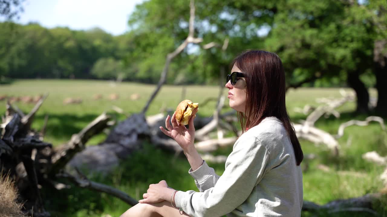 一个女人在大自然中吃三明治。在大自然中远足。视频下载