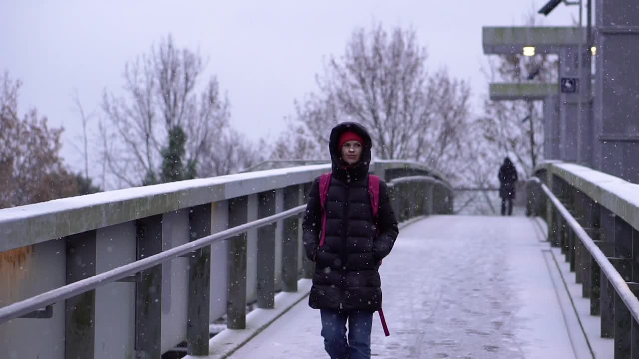 下雪的一天。一位妇女在下雪天走过一座桥。视频下载