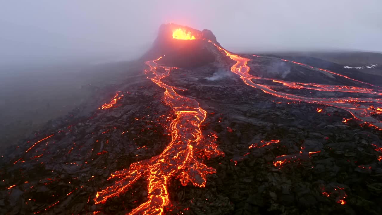一架4K无人机捕捉到冰岛一座活火山快速喷出熔岩的空中电影镜头，随后熔岩在雾蒙蒙的环境中倾泻而下。视频下载