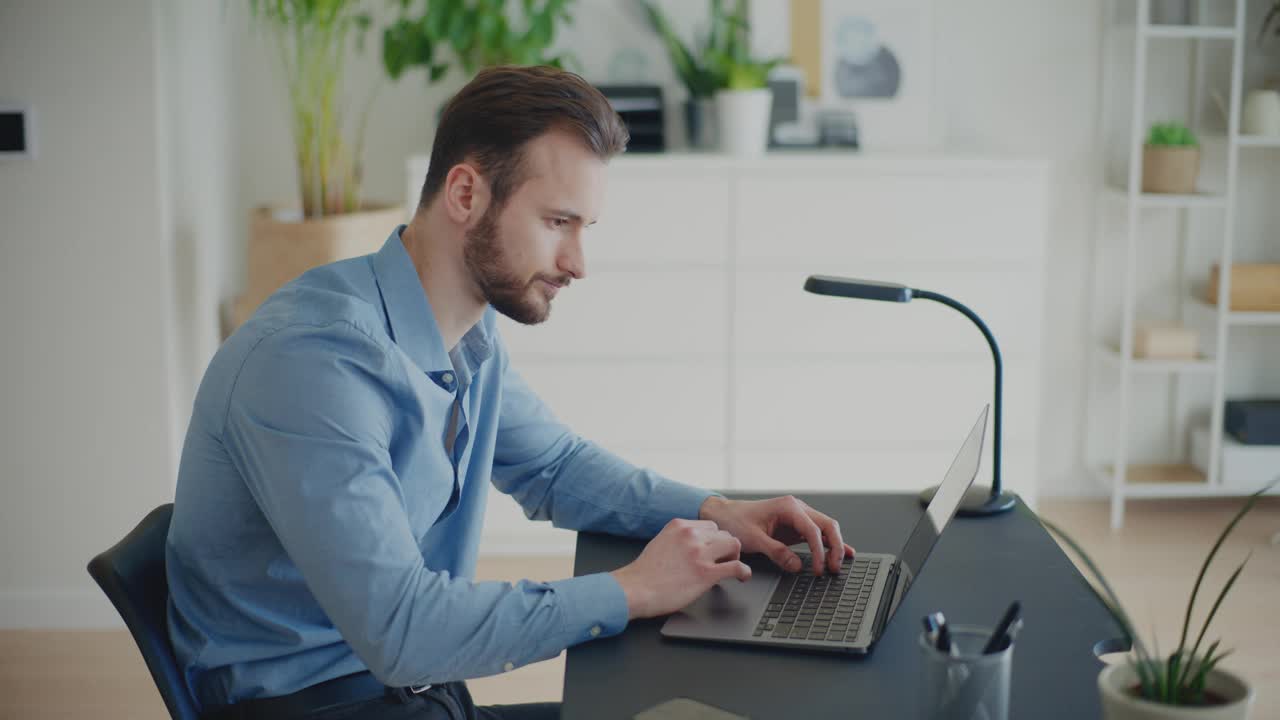 疲惫的年轻商人坐在办公桌前使用笔记本电脑视频下载