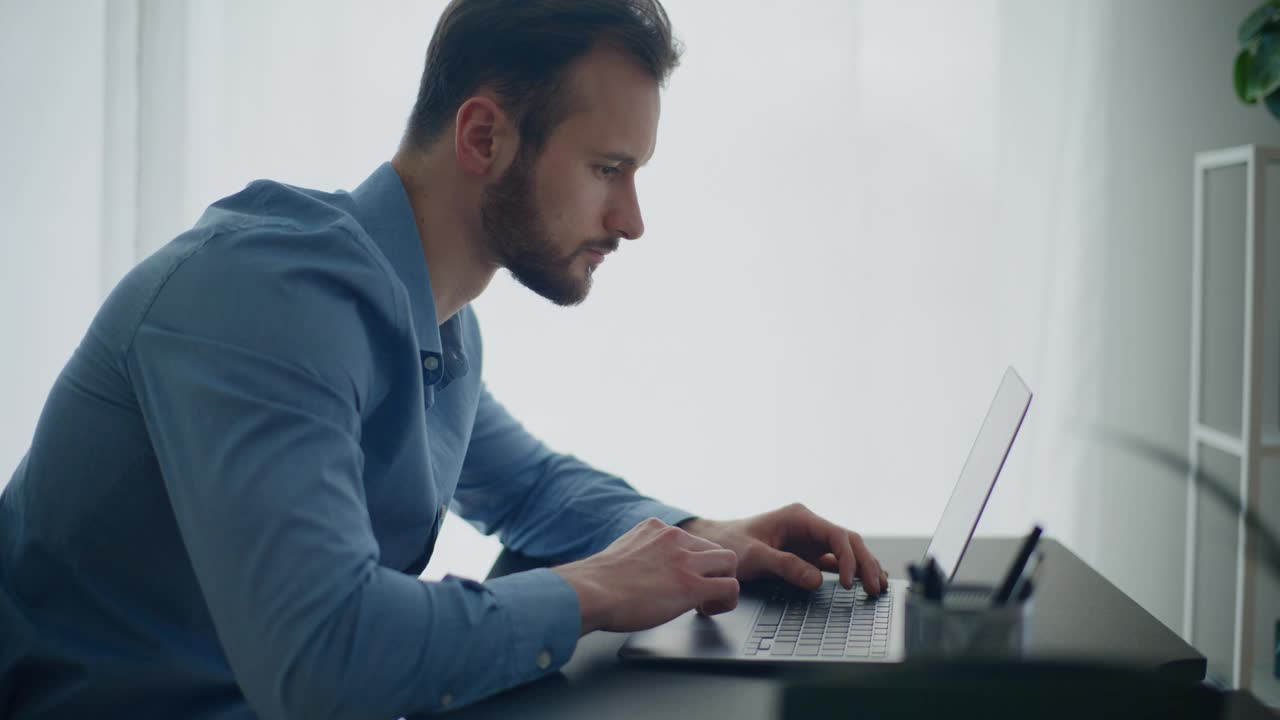 留着胡子的年轻商人在办公桌前用笔记本电脑工作视频下载