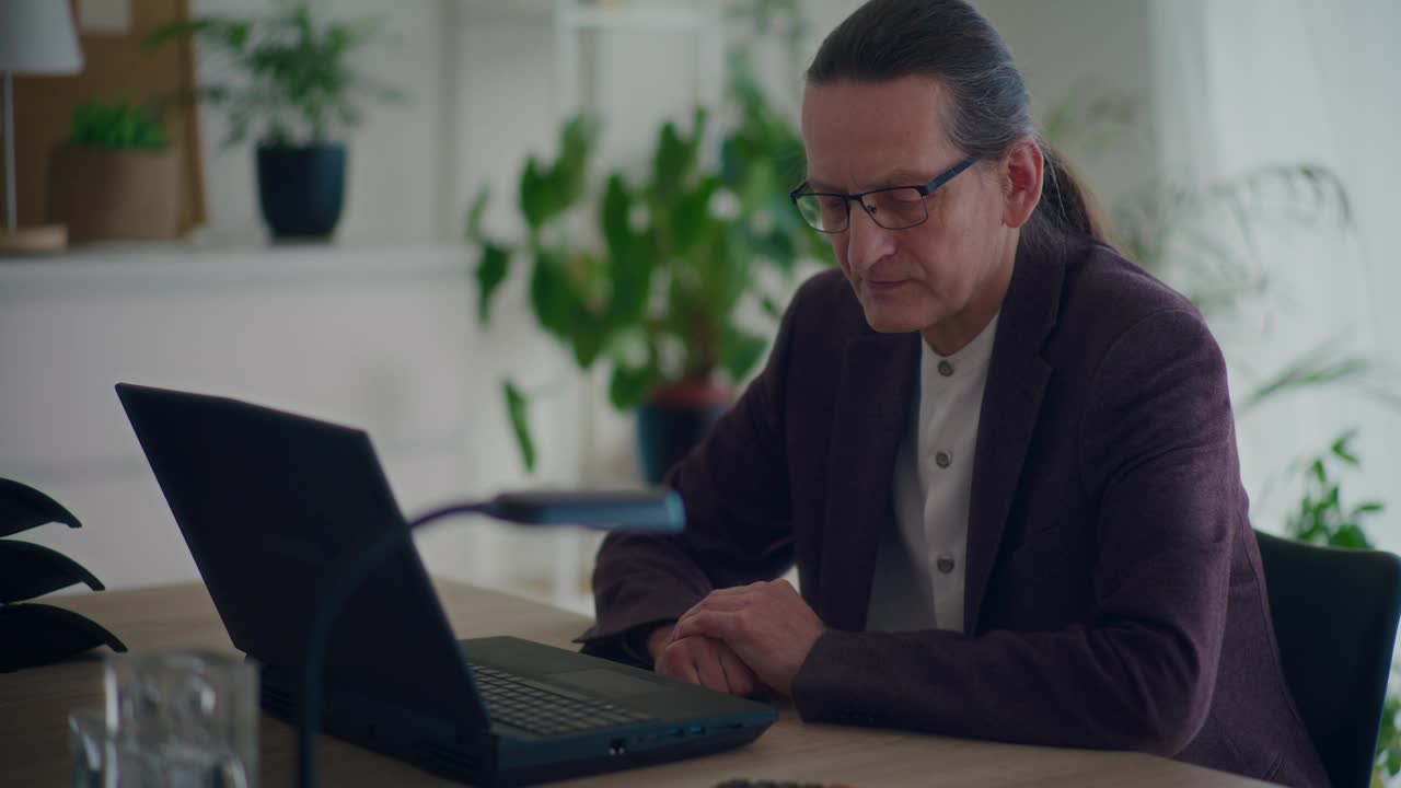 忧心忡忡的资深男性企业家坐在笔记本电脑前视频下载