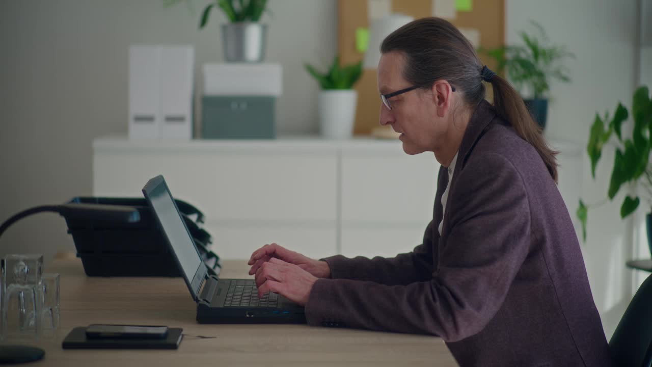资深男性企业家在办公桌前用笔记本电脑打字视频素材