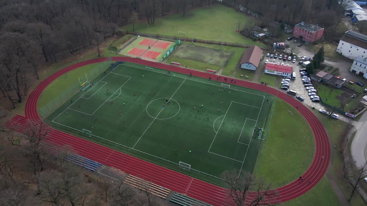 小镇体育场鸟瞰图，球员在足球场上踢足球视频下载