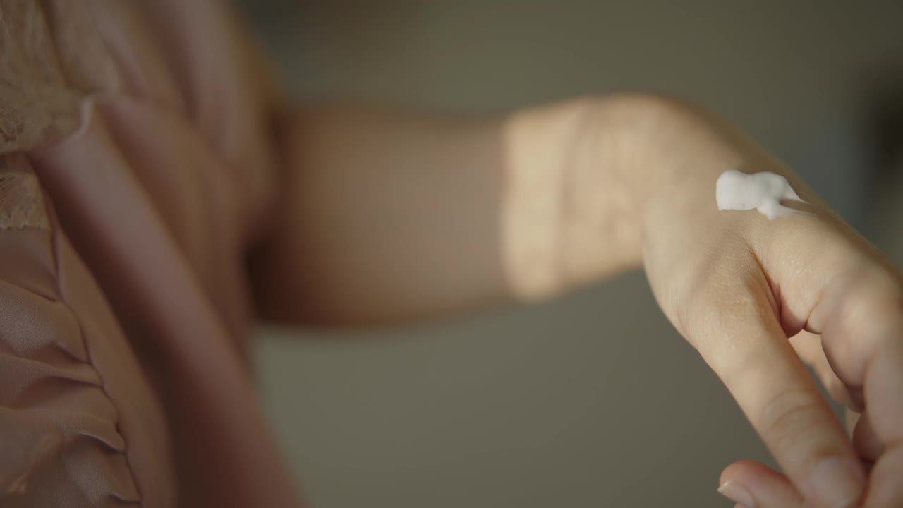 一个亚洲女人在手上擦润肤霜。视频下载