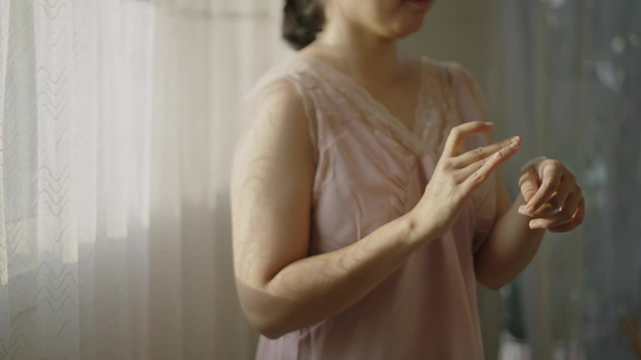 一个亚洲女人在手上擦润肤霜。视频下载