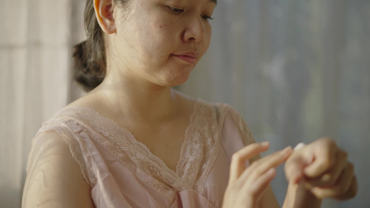亚洲女性用一只手在脸颊上涂抹润肤霜。视频下载