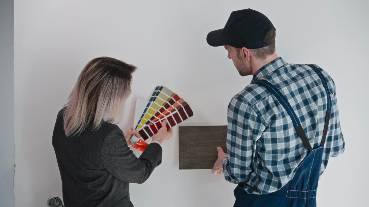一名女设计师和一名建筑承包商选择装修房间的材料和墙壁的颜色。使用调色板和材料样品在建筑工地工作。公寓视频下载