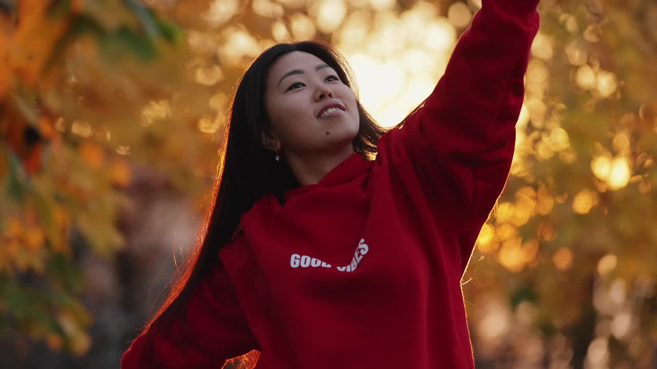 秋天的公园里，一名亚洲女子举手打闹视频下载