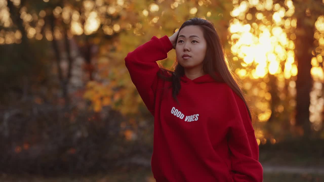 一个亚洲女人在秋天的公园里散步视频下载