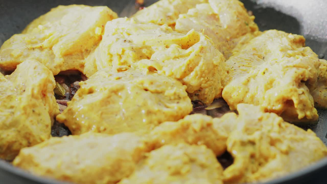 男子将腌制好的鸡肉与炒洋葱一起放入煎锅中，准备鸡肉印度香饭视频下载