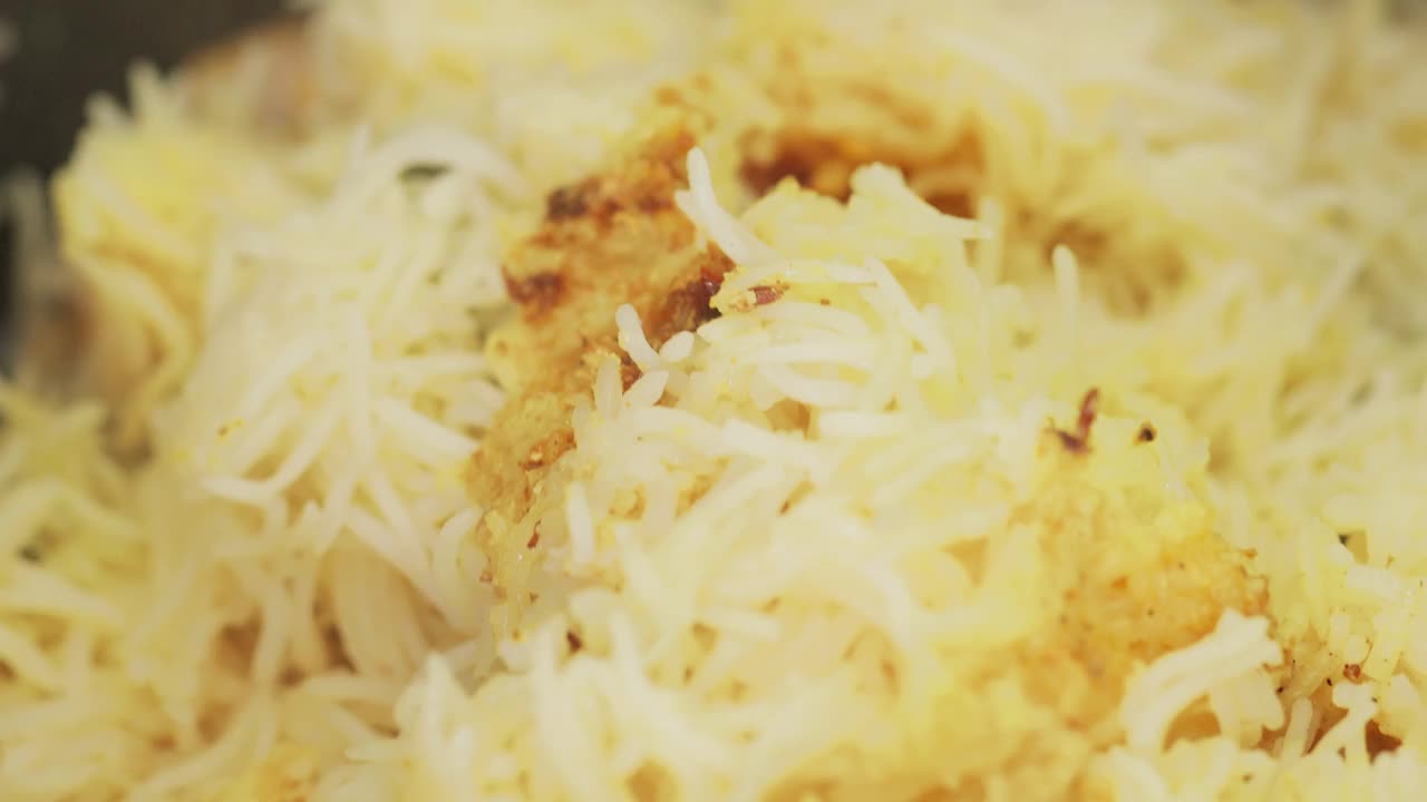 用木铲搅拌煮熟的鸡肉印度香饭，混合米饭和鸡肉，特写视频下载