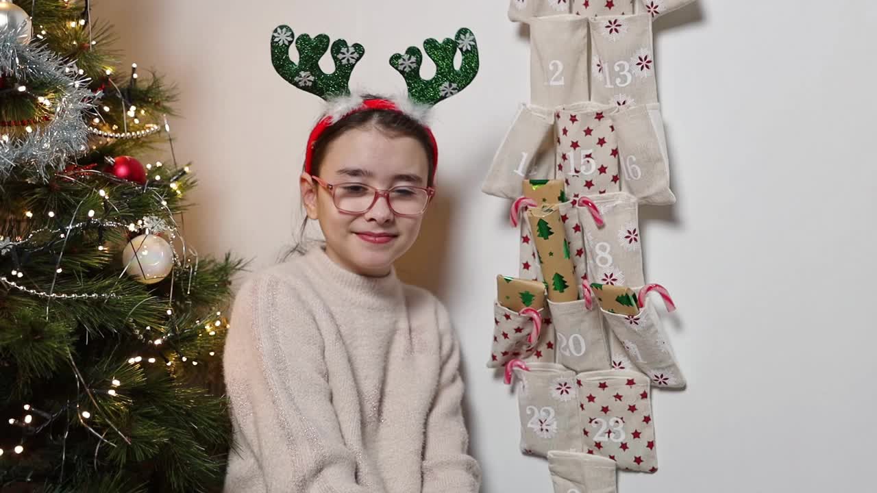 一个女孩从降临节日历上拿出一份圣诞惊喜礼物。视频下载