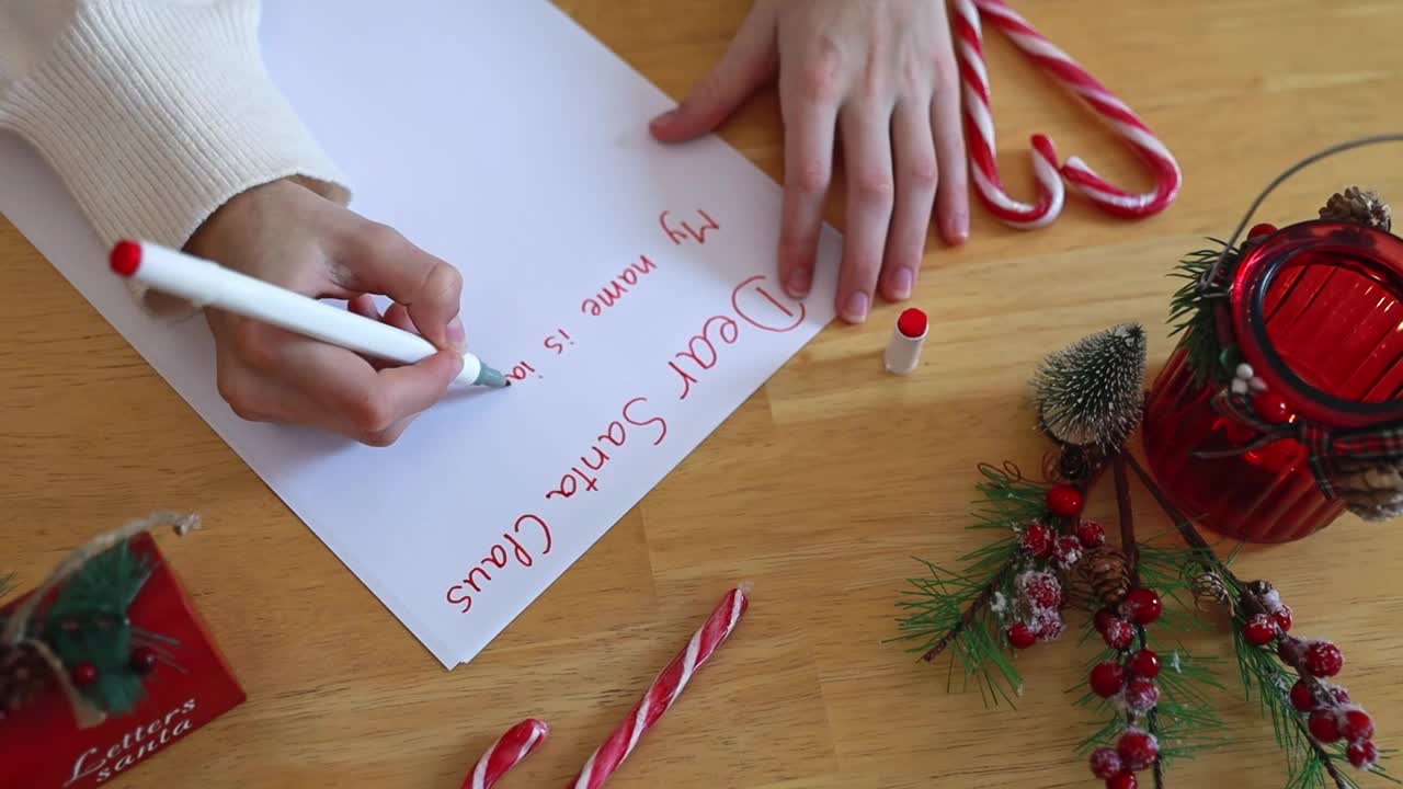 一个十几岁的女孩在餐桌上给圣诞老人写信。视频下载