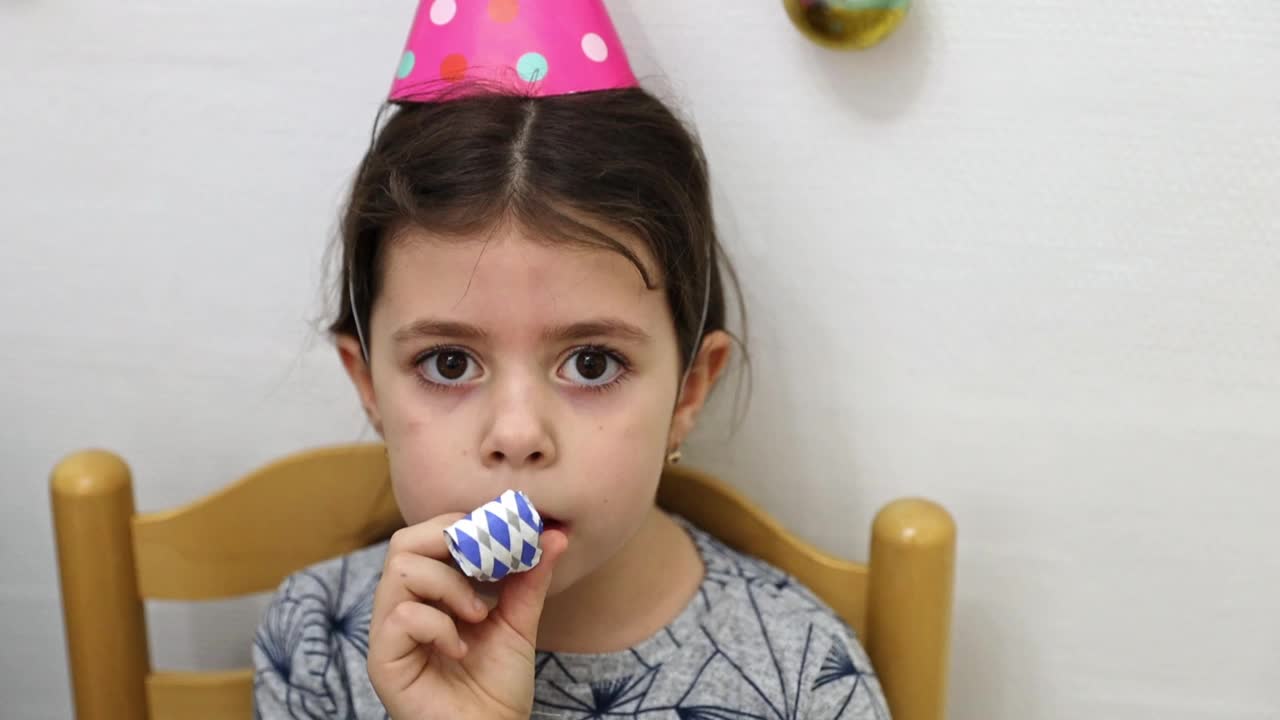 一个小女孩在生日聚会上吹口哨。视频下载