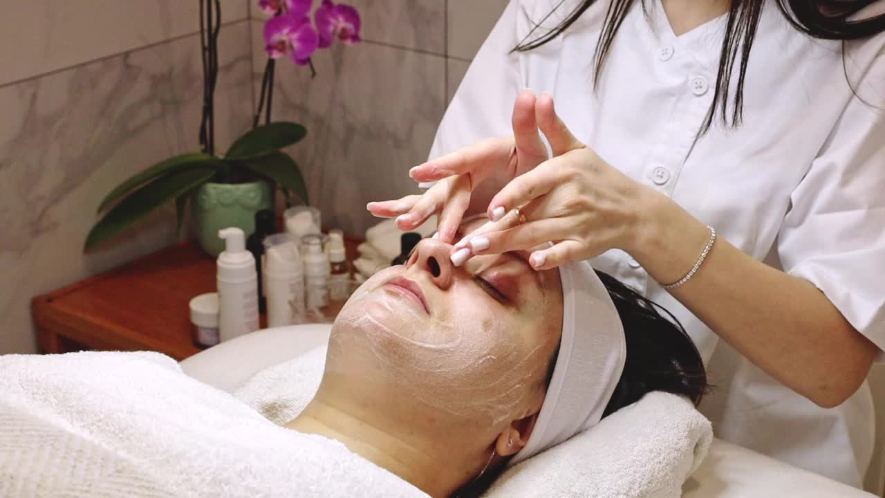 一位女美容师正在给女性的脸部做放松按摩。视频下载