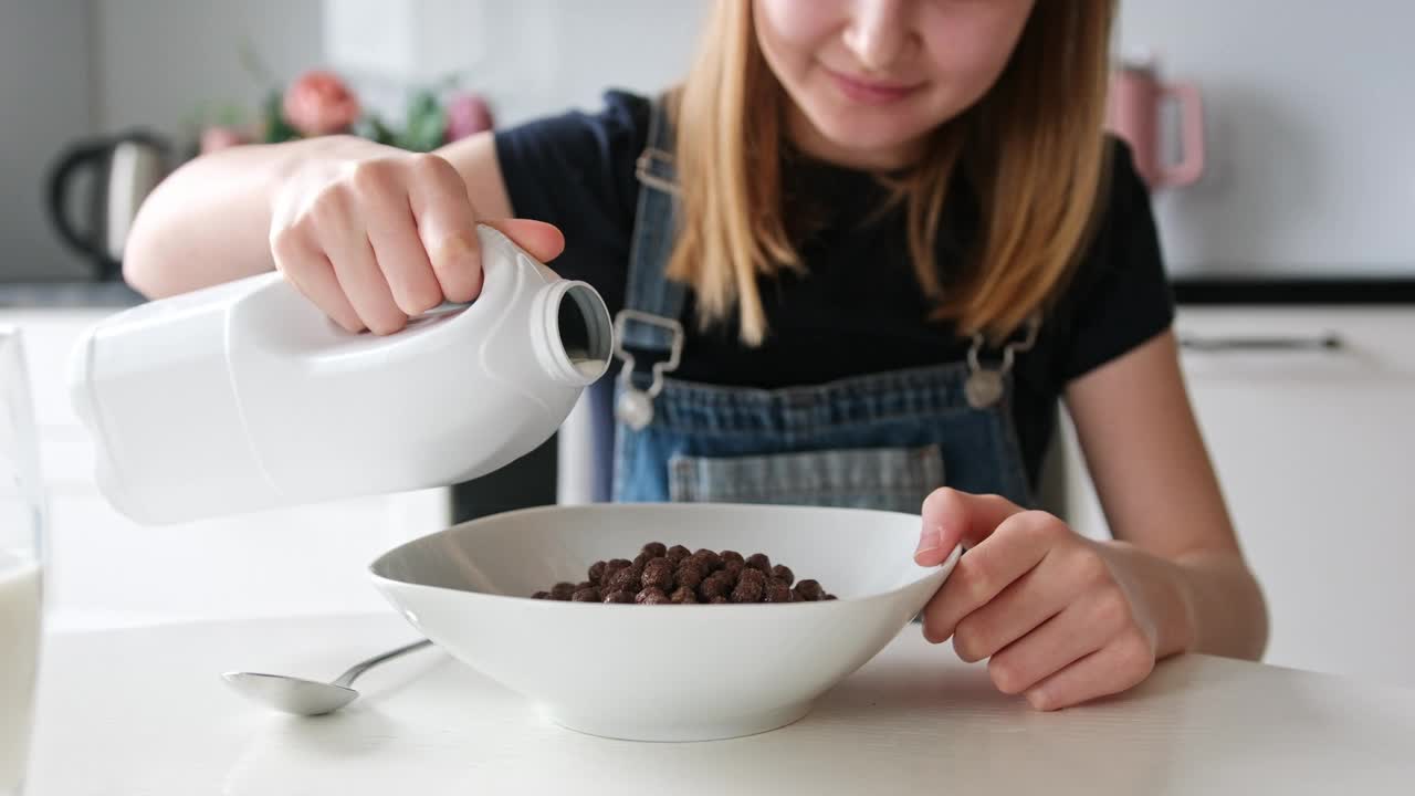 小女孩把牛奶倒入装有棕色巧克力球的盘子里视频下载