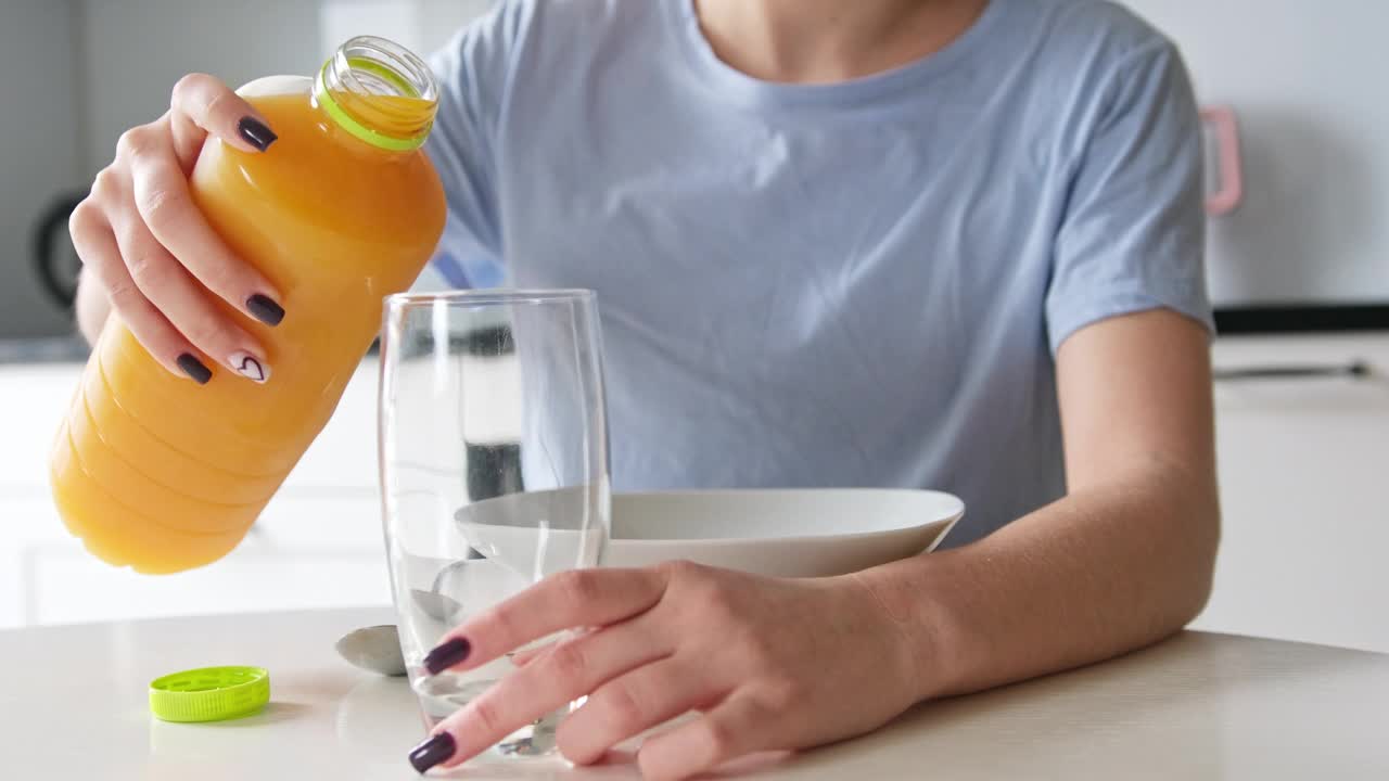 女孩在厨房用玻璃杯倒橙汁当早餐视频下载