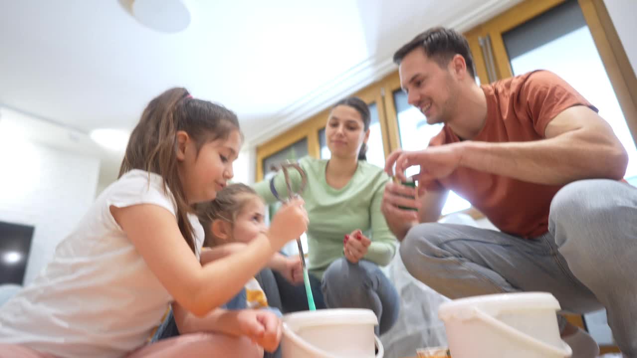 年轻的家庭，白人父母带着女儿粉刷公寓视频下载