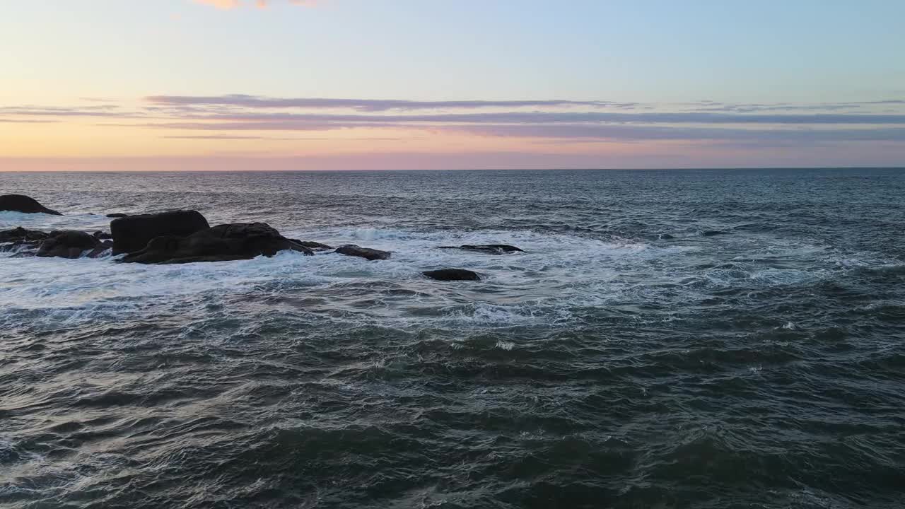 日落画天空和水在温暖的色调，与岩石在前景视频素材