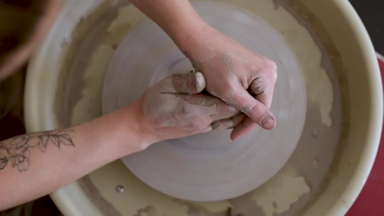 一名年轻女子在陶器作坊里摆弄着陶工的转轮。从上面看视频下载