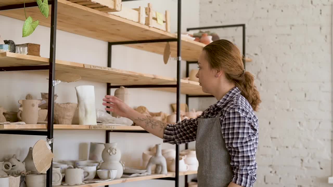 一名年轻的女工匠在陶器作坊里把陶瓷制品放在篮子里视频下载