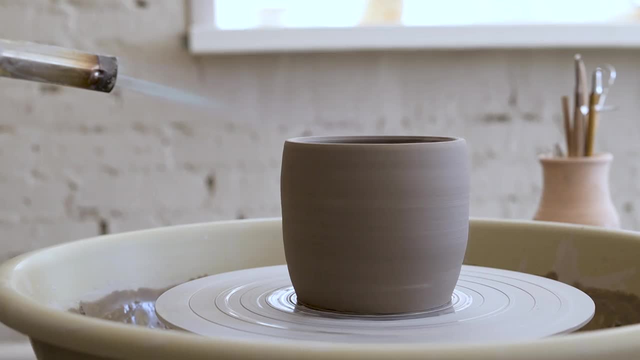 年轻的工匠在烧制一个陶制马克杯。传统陶艺工艺视频下载