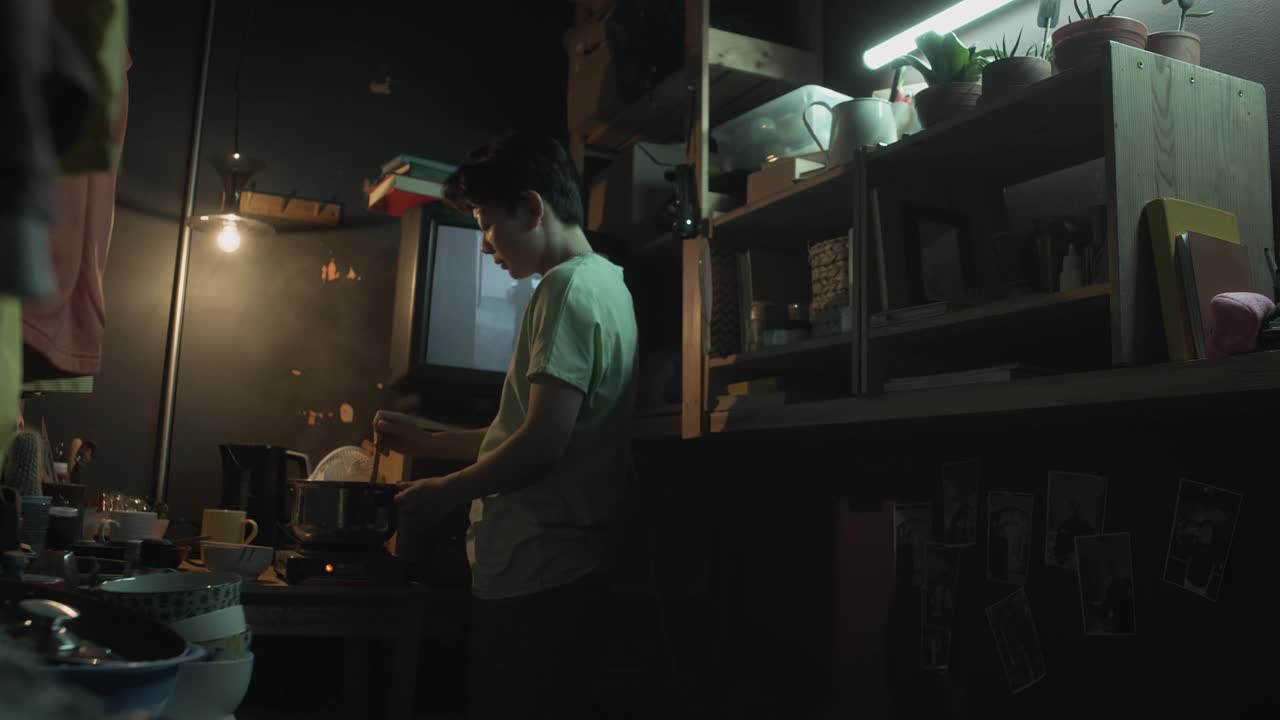 亚洲人在炉子上炒菜，在微型公寓里看电影视频下载